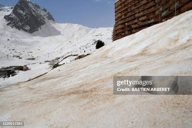 This photograph taken on March 15, 2022 in La Mongie ski ressort shows sand from Sahara that fell overnight covering the snow. - Orange cars, dusty...