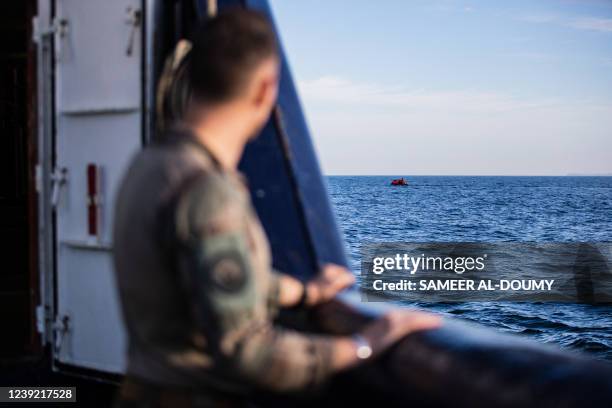 Military officer looks at migrants in a dinghy as they illegally cross the English Channel from France to Britain on March 15, 2022.