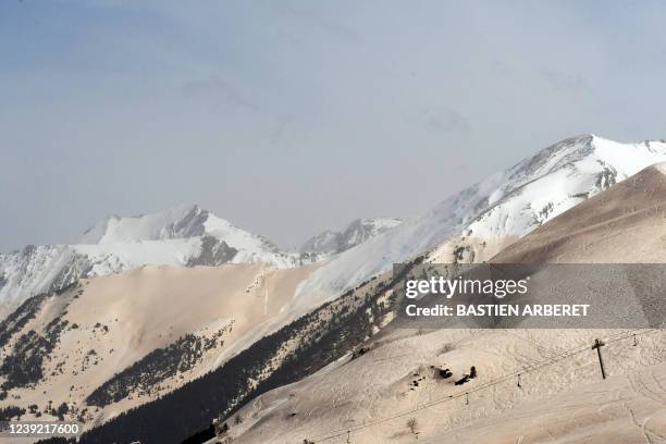 This photograph taken on March 15, 2022 shows sand from Sahara that fell overnight covering the snow, in Piau-Engaly ski ressort, southern France. -...