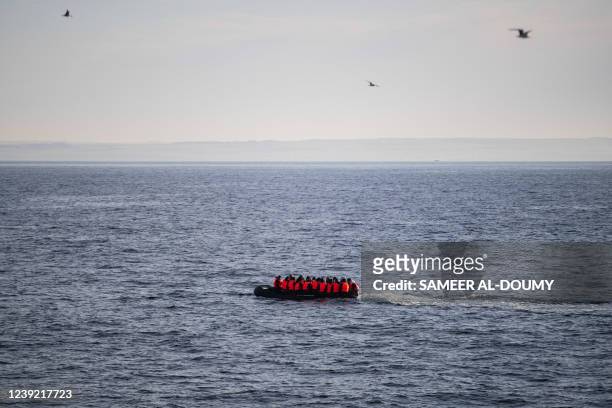 Migrants wearing life jackets sit in a dinghy as they illegally cross the English Channel from France to Britain on March 15, 2022.