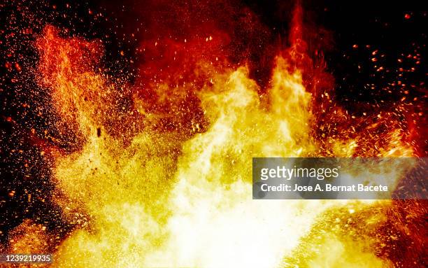 explosion by an impact of a cloud of particles of powder and smoke of color orange and yellow on a black background. - shooting a weapon stock pictures, royalty-free photos & images
