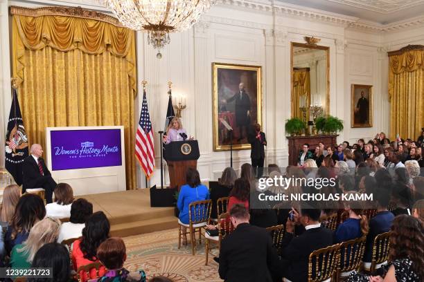 President Joe Biden listens as US First Lady Jill Biden speaks during the Equal Pay Day event to celebrate Womens History Month in the East Room of...