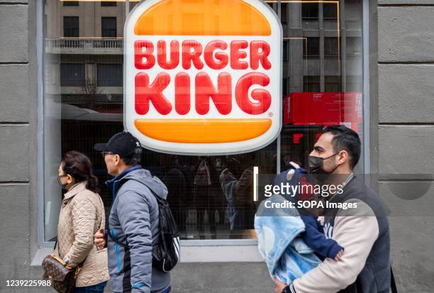 Pedestrians walk past the American chain of hamburger fast food restaurants Burger King in Spain.