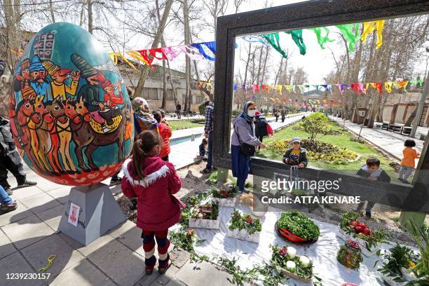 Iranians take photo with a traditional Haftsin, a symbolic arrangement of seven items whose names start with the letter 'S', at a park during an...