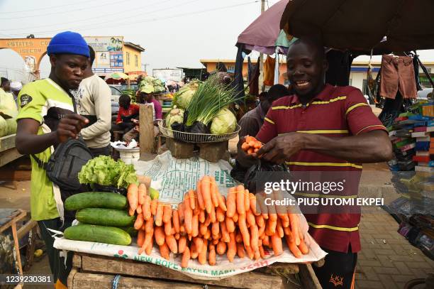 Roadside vendor sells carrots to a buyer in Lagos, Nigeria's commercial capital, on March 14, 2022. - From Nigerian airlines to Malawi bakers,...