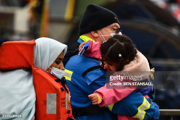 Coastguard carries a child in his arms as he helps migrants to disembark from the UK Border Force vessel Vigilant, after they were picked up at sea...