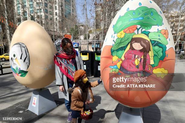Iranians walk past large decorated eggs displayed at a park during an event organised by the municipality of Tehran on March 16 ahead of the...