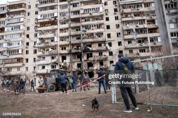 People crowd outside an apartment building half-destroyed by the debris of a missile launched by the Russian army over one of dormitory districts,...