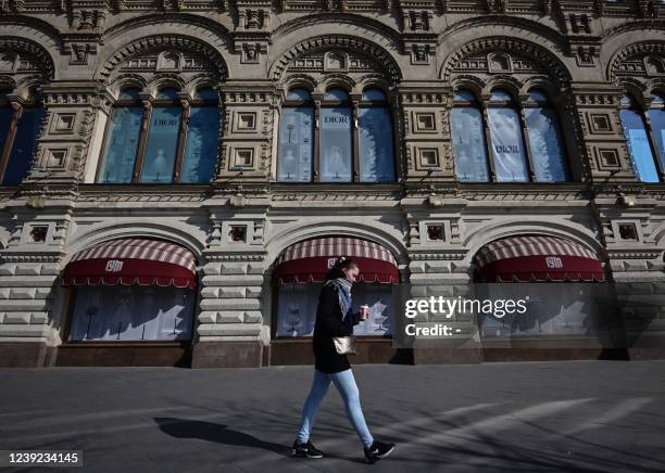 Woman walks past the GUM department store with the windows of the closed Dior boutique in central Moscow on March 16, 2022. - On February 24, Putin...