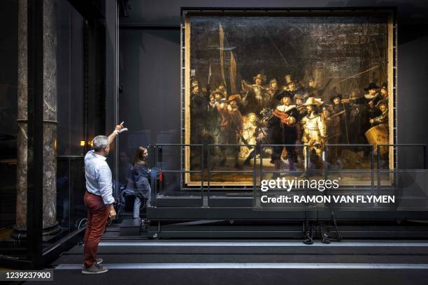 Staff member gives instructions in front of Rembrandt's Night Watch, which has been hung in place again after being stretched on an aluminum frame,...