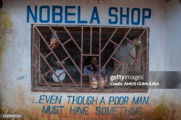 Grocer sits with four loaves of bread waiting for customers in the suburb location of Area 23 in the capital Lilongwe, Malawi, March 16, 2022. - From...