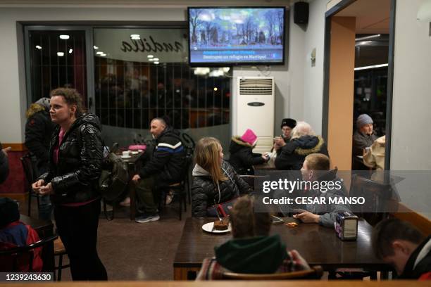 Ukrainian refugees, carried by the convoy of Spanish taxi drivers, watch television broadcasting images of the war in Ukraine, during a stop at a...