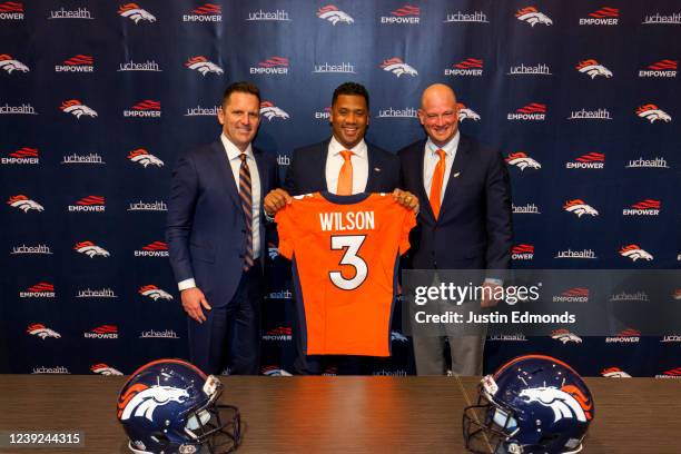 Quarterback Russell Wilson of the Denver Broncos poses with his jersey alongside General Manager George Paton and Head Coach Nathaniel Hackett...