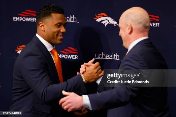 Quarterback Russell Wilson of the Denver Broncos shakes hands with head coach Nathaniel Hackett during an introductory press conference at UCHealth...