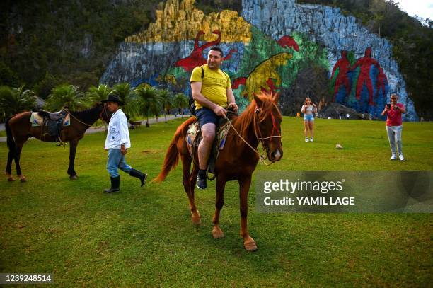 Tourist rides a horse by the Mural of Prehistory in Vinales, Pinar del Rio province, Cuba, on February 19, 2022. - Vinales, a town with an incipient...