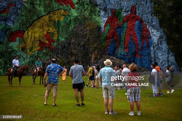 Tourists look at the Mural of Prehistory in Vinales, Pinar del Rio province, Cuba, on February 19, 2022. - Vinales, a town with an incipient tourism...