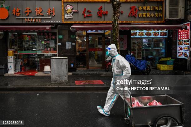 Worker wearing protective gear walks near a locked down neighbourhood after the detection of new cases of Covid-19 in the Huangpu district of...