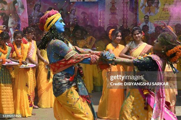 Youths smeared in coloured powder and dressed as Lord Krishna and deity Radha celebrate with others the Holi festival, the Hindu spring festival of...