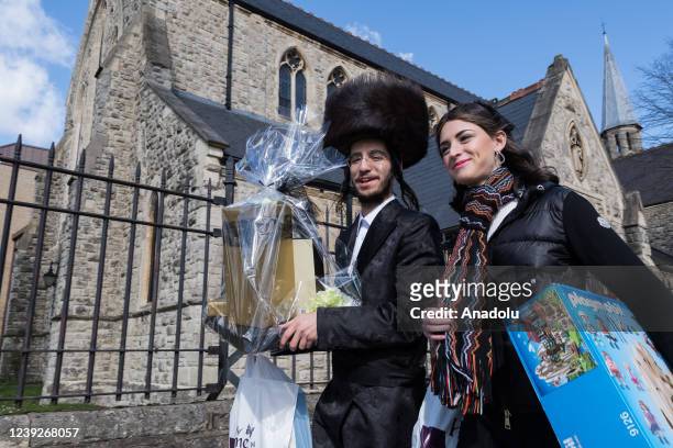 Orthodox Jewish couple carry gifts during the annual holiday of Purim on the streets of Stamford Hill in London, United Kingdom on March 17, 2022....