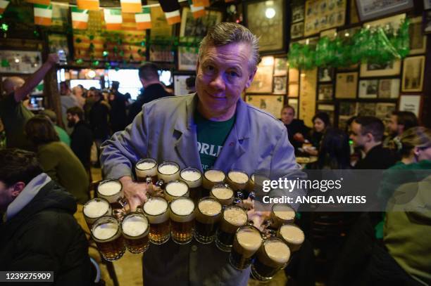 Waiter holds a large quantity of beer to serve to his customers at McSorley's Old Ale House on St. Patrick's Day, March 17, 2022 in New York City. -...