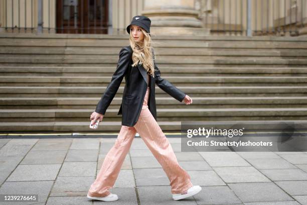 German model Anna Hiltrop wearing a black leather blazer by Zara, bralette by Jacquemus, pastel peach colored silk pants by Off-White, a black bucket...