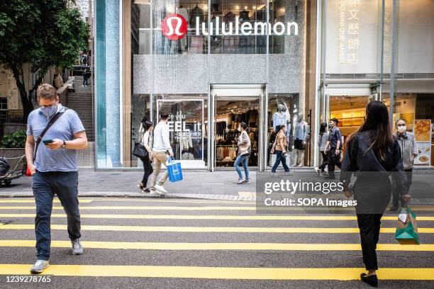 People wearing surgical masks walk by a Lululemon store in the Central Business District of Hong Kong. According to the Hong Kong Government's...