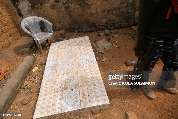 Nigerian police officer stands beside the burial ground of the late Alata Manga, chief of Manga Village, that borders Nigeria and Cameroon, on...