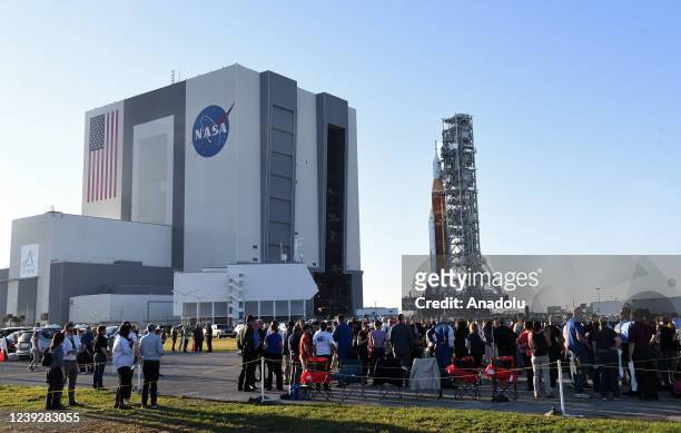 People watch as NASAâs SLS moon megarocket topped by the Orion spacecraft rolls out of the Vehicle Assembly Building at the Kennedy Space Center on...