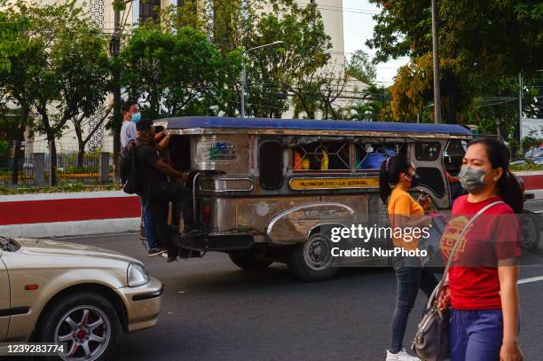 In this picture taken on 9 March 2022, passengers of a jeepney, a unique type of public transport in the Philippines, hang on its footsteps, as...