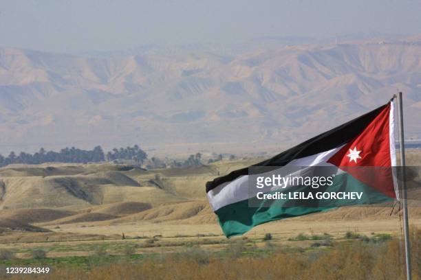 Jordanian flag billows in front of a view of Israel 18 January 2002 at Maghtas near the Jordan River, about 45 km southwest of Amman. The area has...