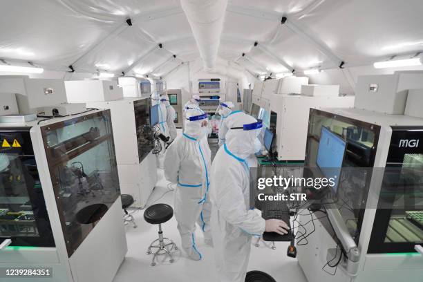 This photo taken on March 17, 2022 shows staff members, wearing personal protective equipment , working at the Fire Eye laboratory, a temporary...