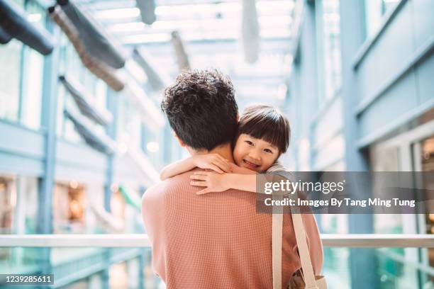 rear view of young dad embracing his lovely little daughter in shopping mall - family mall stockfoto's en -beelden