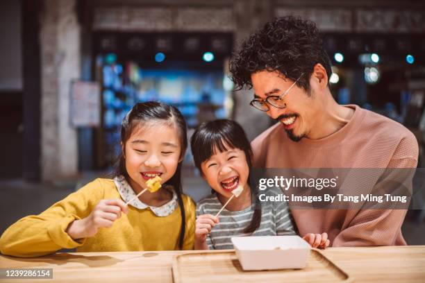 dad & little daughters having local snacks joyfully in a snack shop - asian family cafe stockfoto's en -beelden