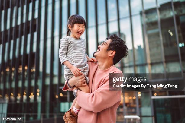 dad holding up and playing with his little daughter joyfully against a modern building in city - china modern city bildbanksfoton och bilder