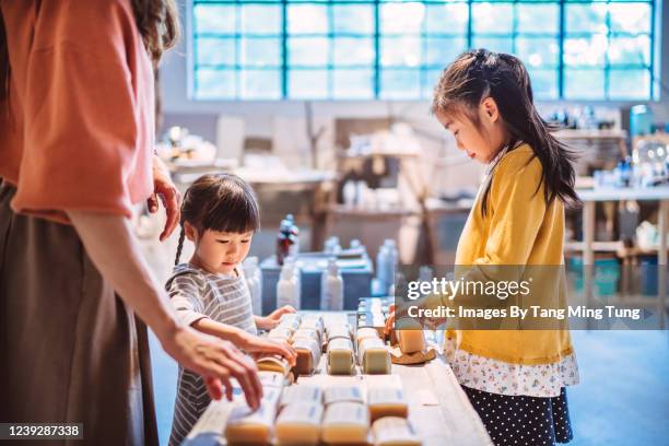 little sibling shopping for organic bodycare products with their mom in a store joyfully - asian family shopping foto e immagini stock