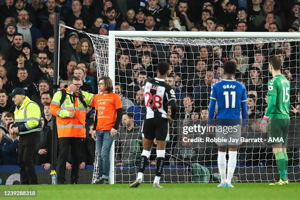 Protestor ties his head to the goal post which interrupted play wearing a t-shirt saying Just Stop Oil during the Premier League match between...