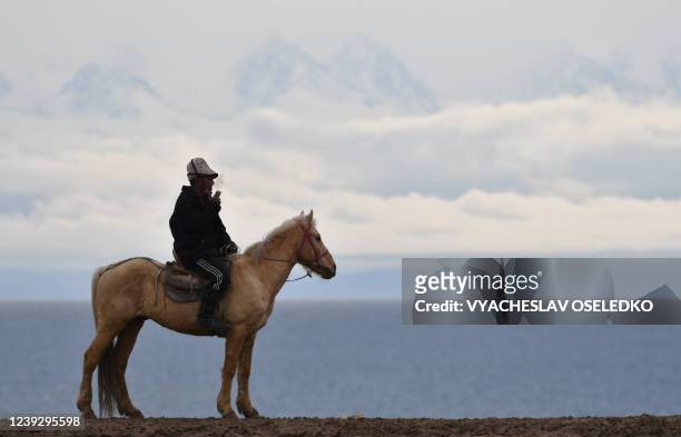 Man smokes as he sits on a horse while Kyrgyz riders play the traditional Central Asian sport of Kok-Boru or Buzkashi in Cholpon-Ata near Issyk-Kule...