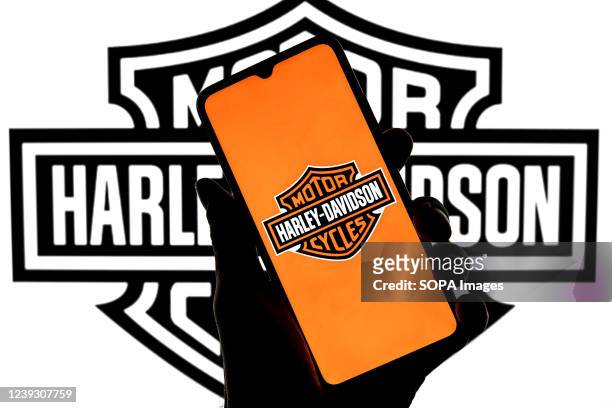 In this photo illustration a Harley-Davidson logo seen displayed on a smartphone with a Harley-Davidson logo in the background.