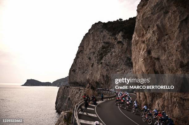 The pack rides along the coastline near Varigotti, Liguria, during the 113th Milan-San Remo one-day classic cycling race, on March 19, 2022 between...