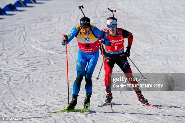 Quentin Fillon Maillet of France and Sturla Holm Laegreid of Norway compete during the men's 12,5 km pursuit event of the IBU Biathlon World Cup in...