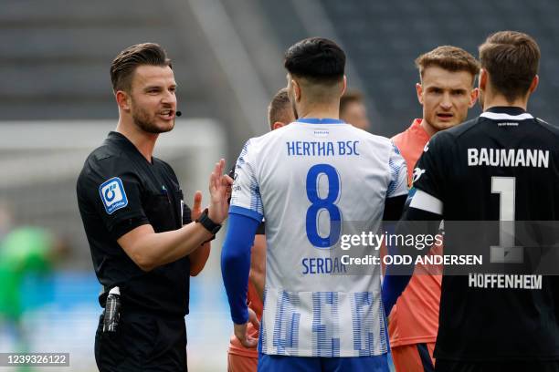 German referee Daniel Schlager speaks with Hertha Berlin's German midfielder Suat Serdar and Hoffenheim's German goalkeeper Oliver Baumann during the...