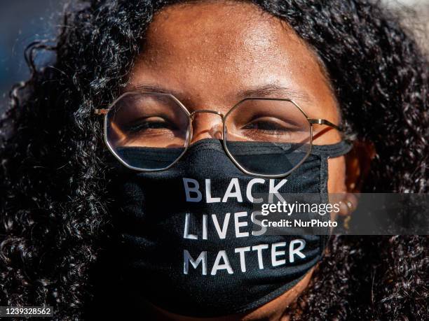 Black woman is wearing a mouth mask with the message Black Lives Matter on it, during the demonstration against racism in Amsterdam, on March 19th,...
