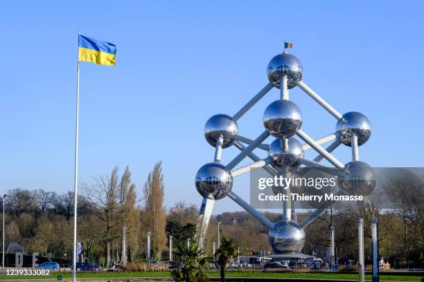 The Ukrainian flag is seen beside the Atomium in the Heysel Plateau on March 19, 2022 in Brussels, Belgium. The Atomium is a monument in Brussels,...