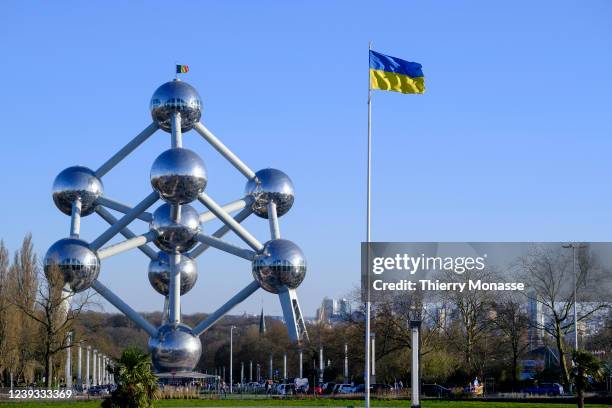 The Ukrainian flag is seen beside the Atomium in the Heysel Plateau on March 19, 2022 in Brussels, Belgium. The Atomium is a monument in Brussels,...