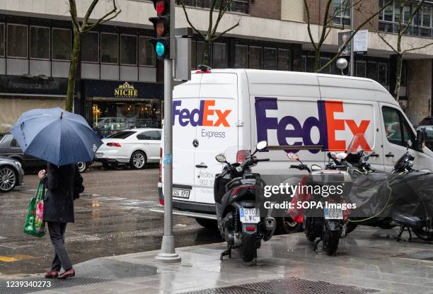 Pedestrian walks past the American FedEx Express delivery van in Spain.