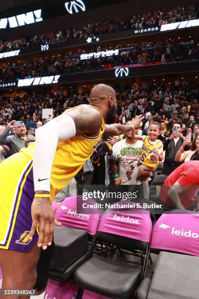 LeBron James of the Los Angeles Lakers hi-fives a fan after the game against the Washington Wizards on March 19, 2022 at Capital One Arena in...