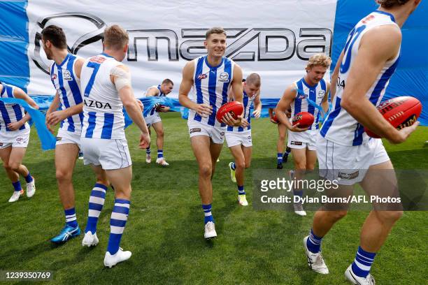 Callum Coleman-Jones of the Kangaroos and Jason Horne-Francis of the Kangaroos run through the banner during the 2022 AFL Round 01 match between the...