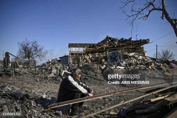 Man sits in front of a destroyed house after bombardments in the village of Krasylivka, east of Kyiv, on March 20 as Russian forces try to encircle...