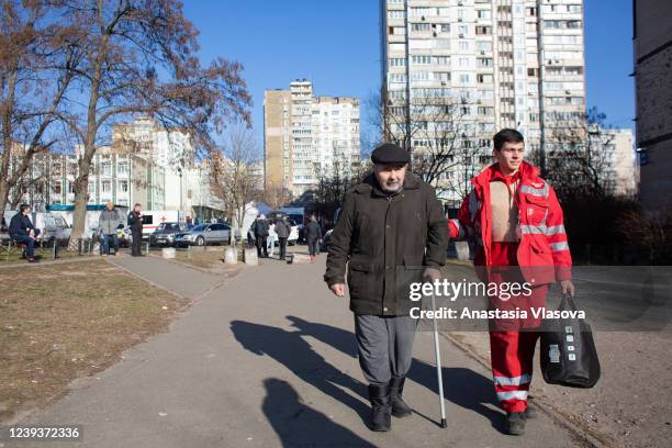 The Red Cross worker assist an elderly person to leave the area which got hit with a shellfire on March 20, 2022 in Kyiv, Ukraine. Russian forces...