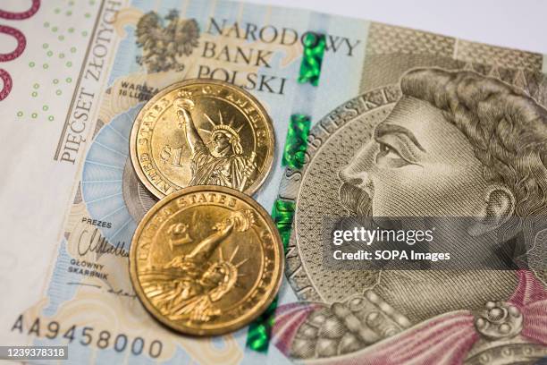 In this photo illustration, the reverse of the United States 1 dollar coins with Statue of Liberty and Polish 500 zloty banknote are seen displayed.